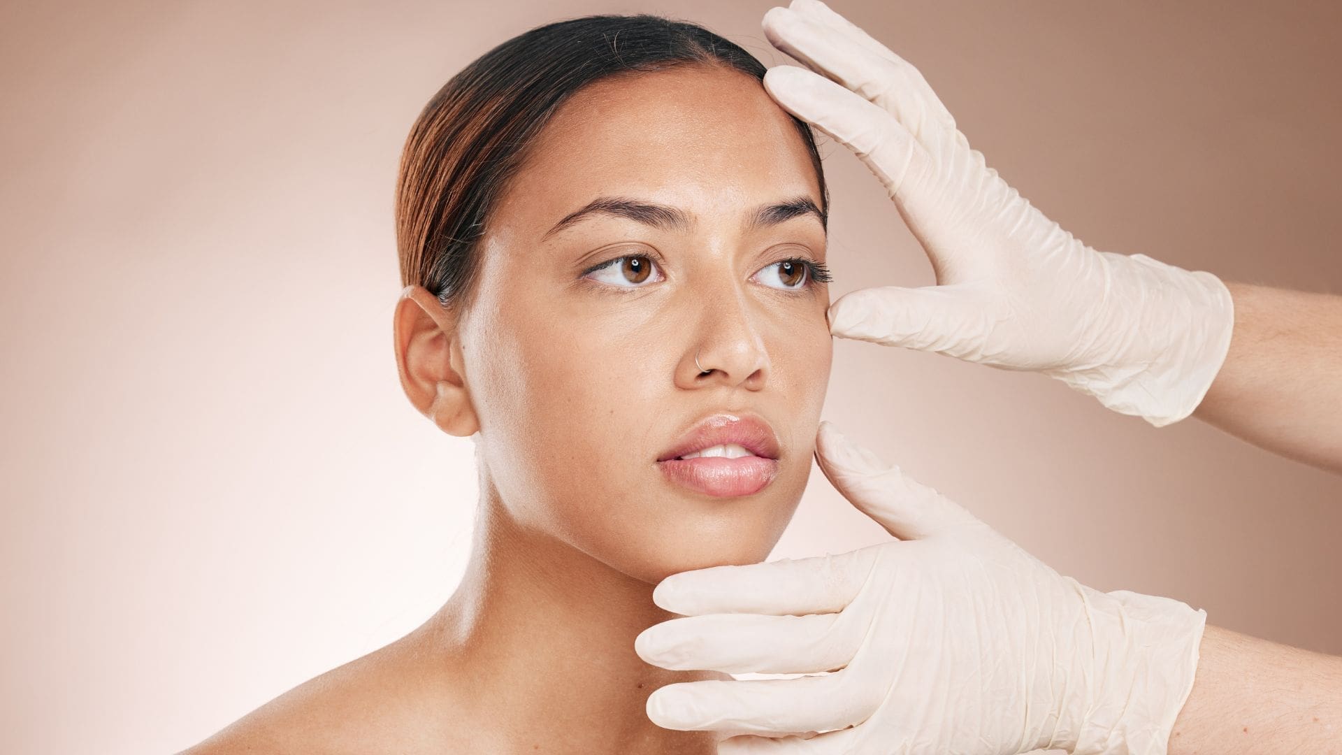 Young woman with clear skin and a gloved hand, representing Towson Med Spa's chemical peel aesthetic treatments.