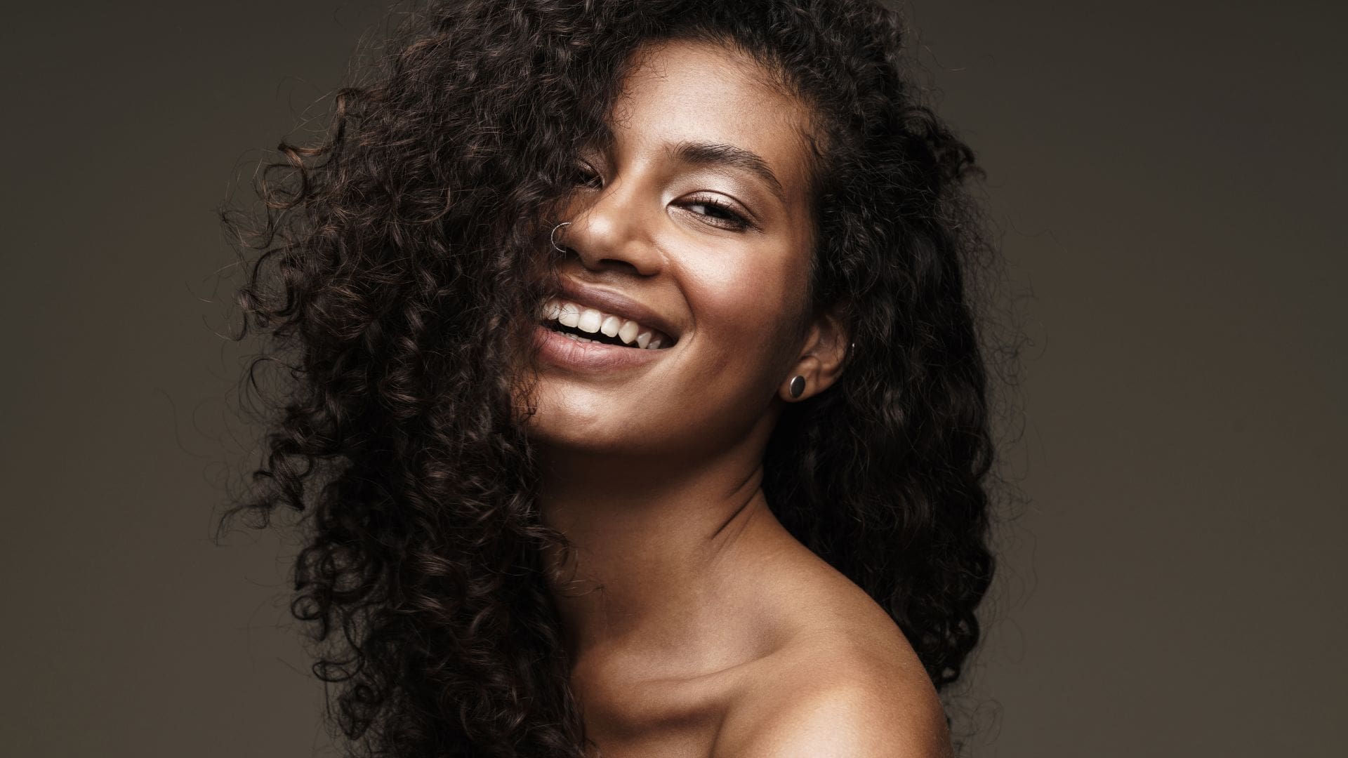 Smiling woman with curly hair, showcasing natural beauty at Body Scientific Aesthetics' laser hair removal clinic.