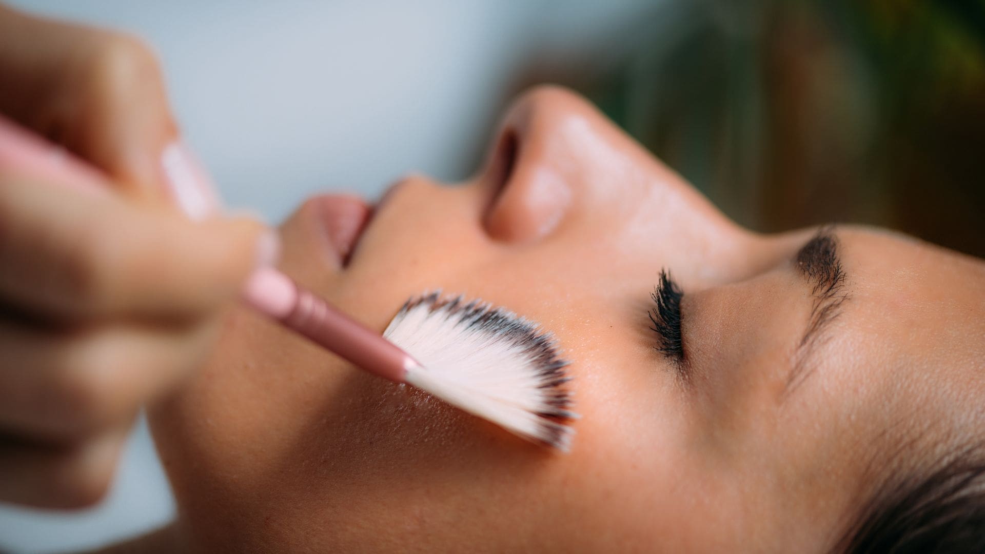 Woman receiving a chemical peel treatment with a brush applied to her face, emphasizing skincare and aesthetic services in Towson, MD.