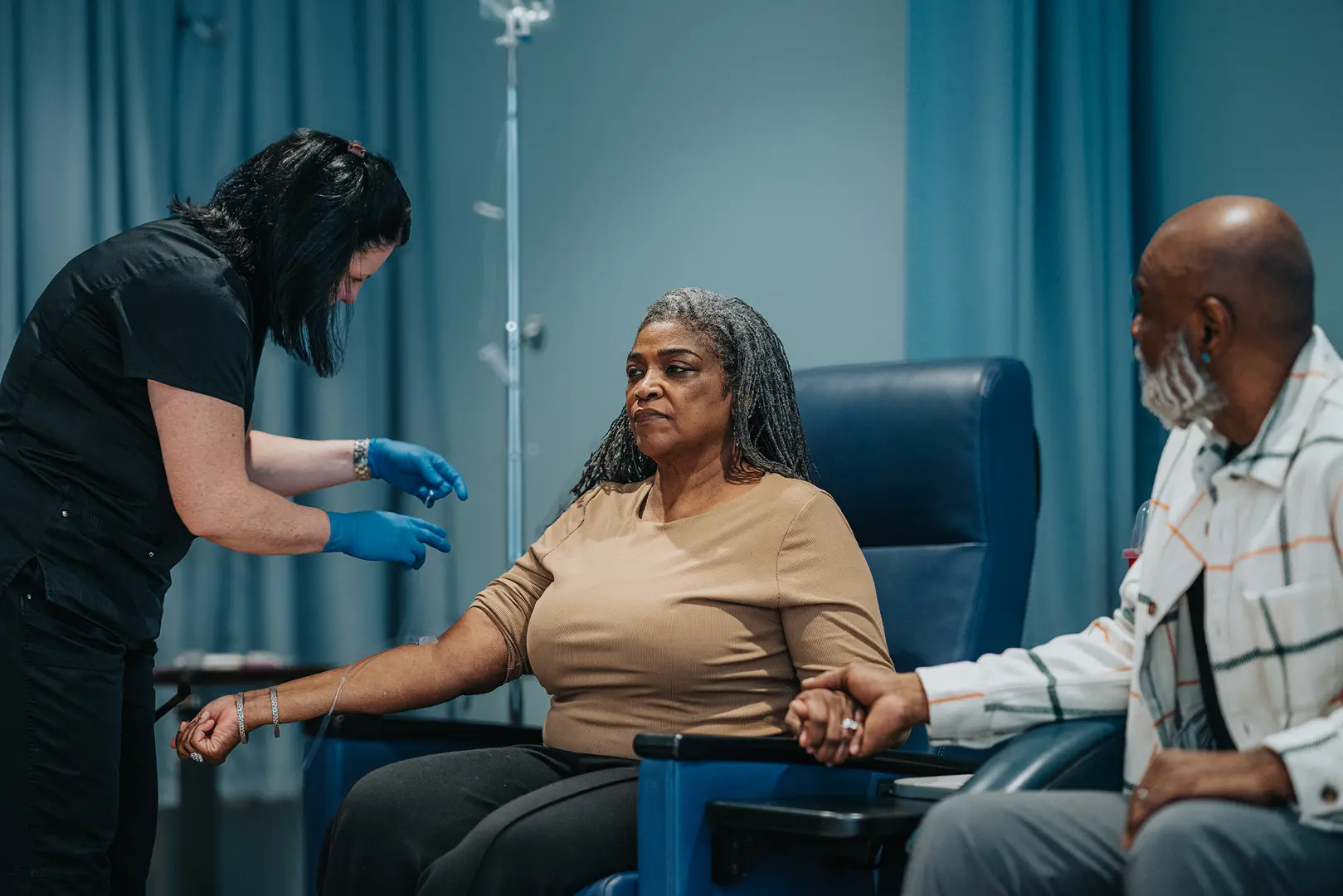 A woman donating blood while medical staff assist her.