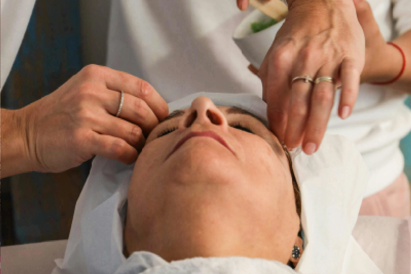 A woman receiving a facial massage with hands gently pressing her face.