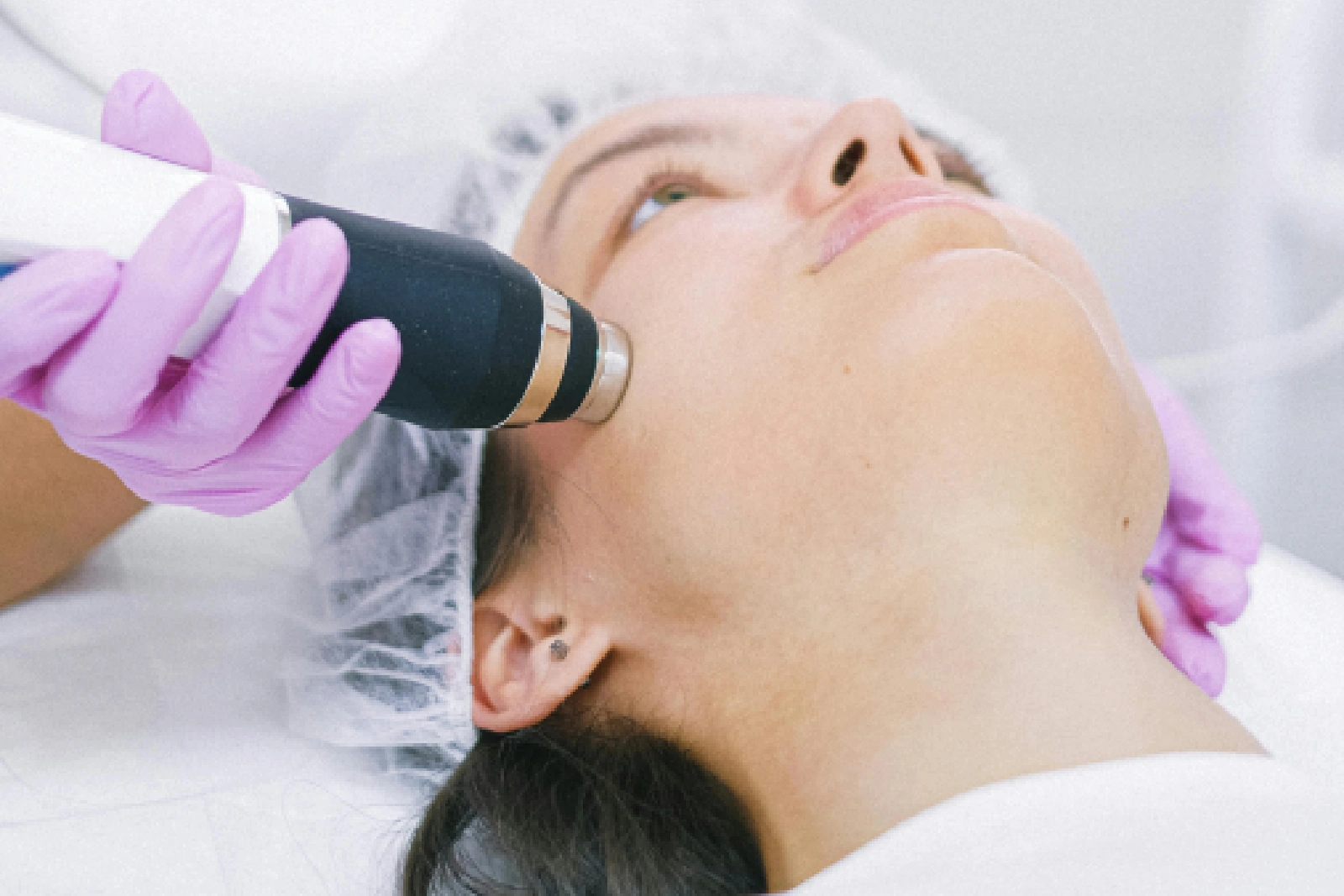 A woman receiving a facial treatment with a handheld device.