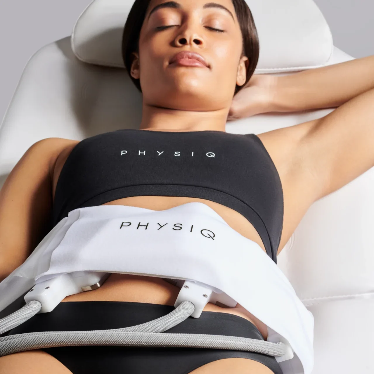 Woman relaxing with a Physiq cold therapy device on her abdomen.