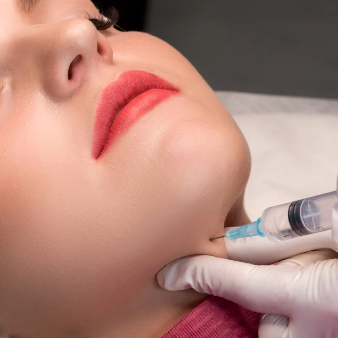 Close-up of a woman receiving a cosmetic injection in the chin.