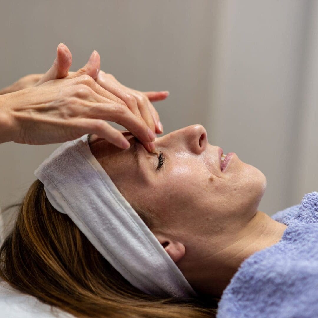 A woman receiving a relaxing facial massage at a spa.