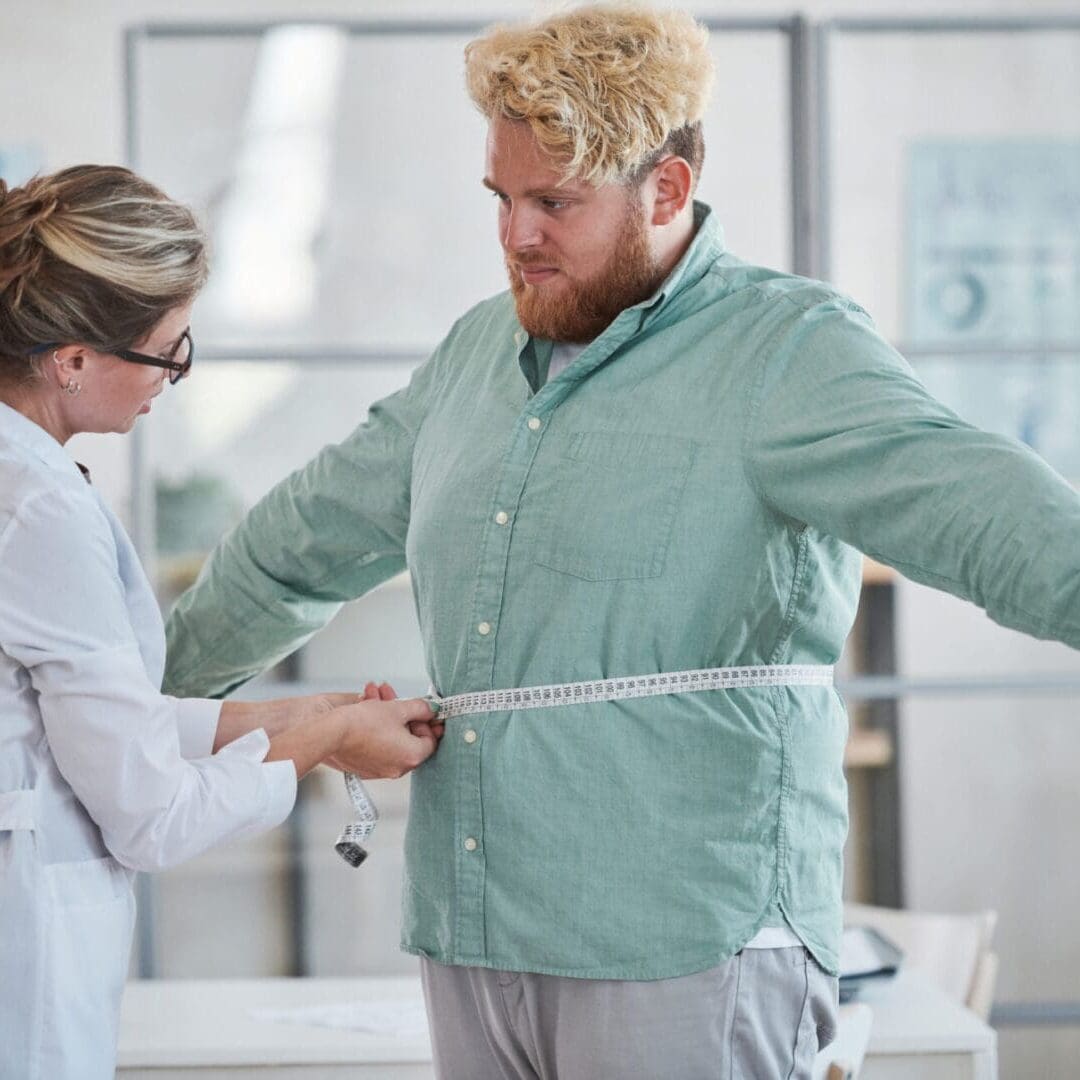A man getting his waist measured by a healthcare professional.
