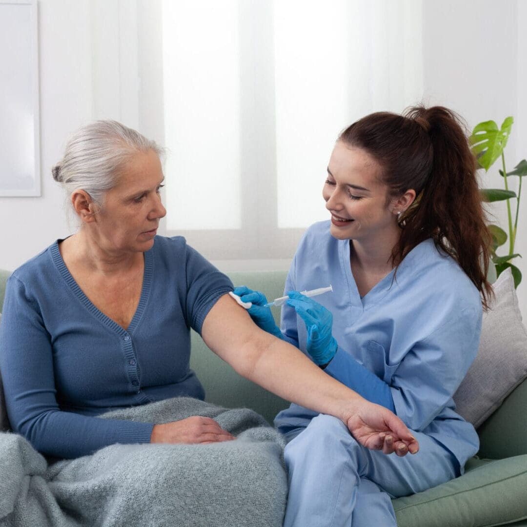 A nurse measures blood pressure of a smiling elderly woman at home.