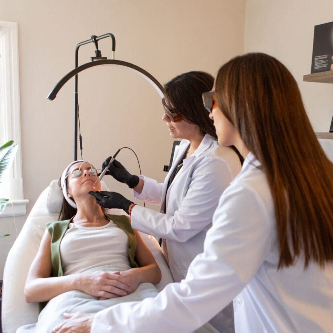 Two medical professionals examining a patient's eyes with a slit lamp.