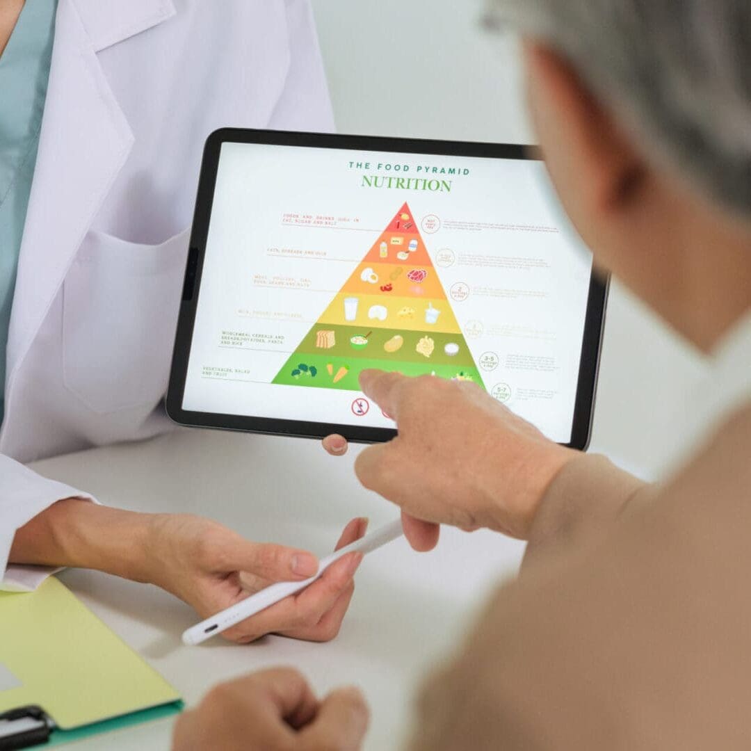 Person pointing at a nutrition pyramid on a tablet during a consultation.