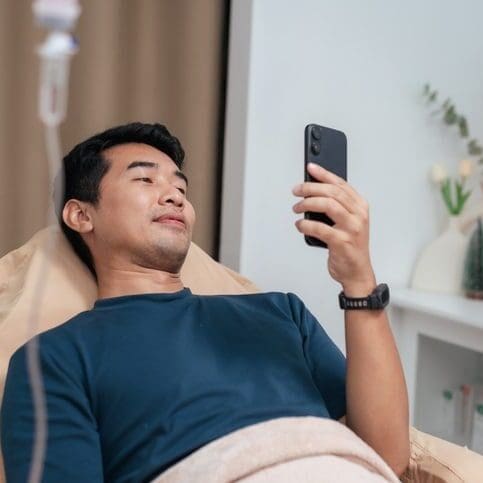 Man lying in bed looking at his phone.