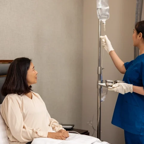 Nurse adjusting IV drip while patient waits.