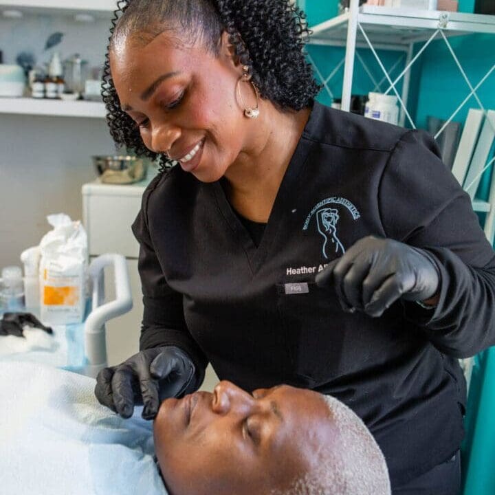 A beautician carefully works on a client's face in a treatment room.