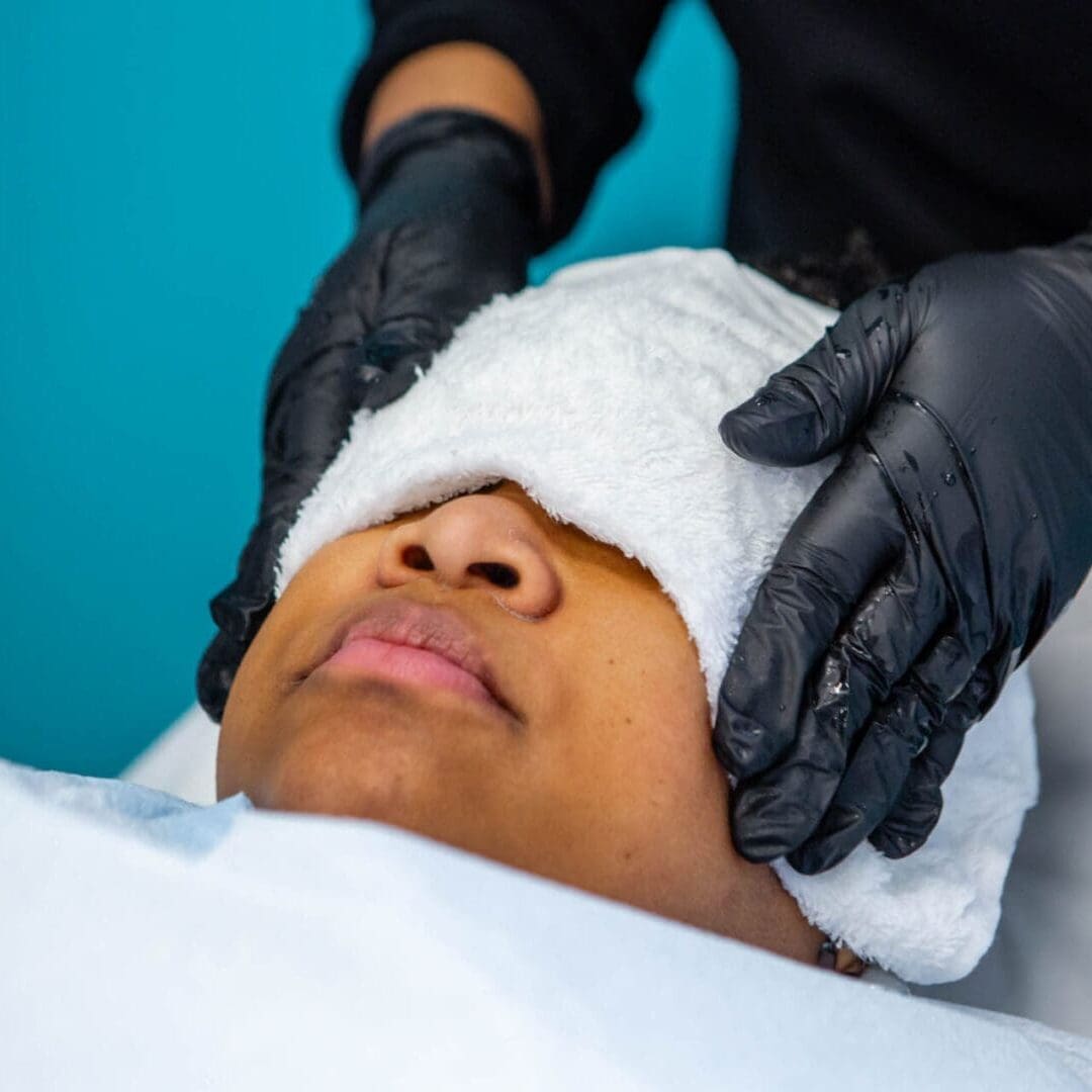 Person receiving a facial treatment with eyes covered by a towel.