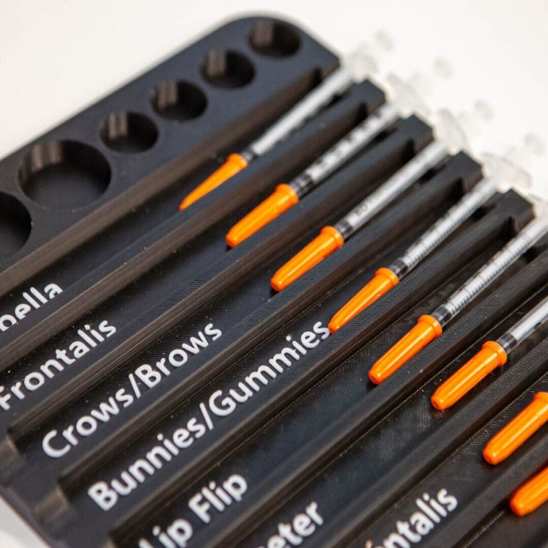 A collection of black pens with orange clips, each labeled with unique names.